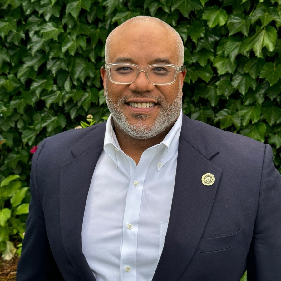 Dr. Stephen Thompson smiling outdoors in front of green ivy